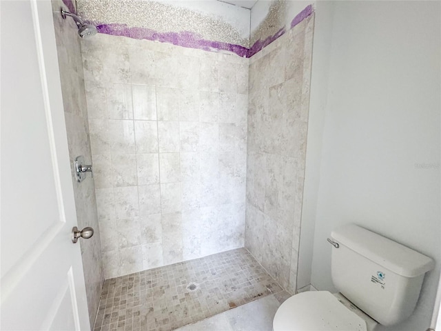 bathroom featuring tiled shower and toilet