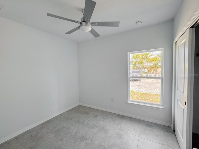 spare room with ceiling fan and baseboards