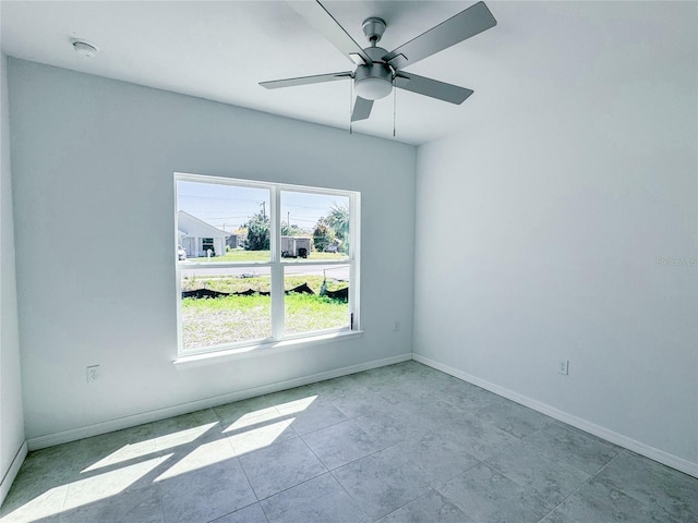 unfurnished room featuring a ceiling fan and baseboards