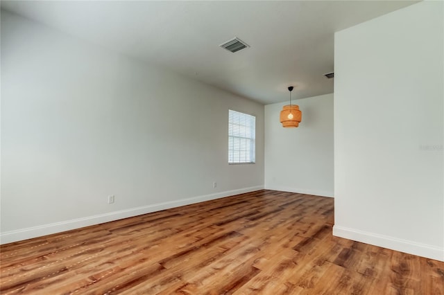 empty room with visible vents, baseboards, and wood finished floors