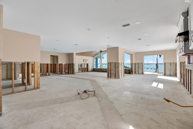 empty room featuring a wealth of natural light, visible vents, and unfinished concrete flooring