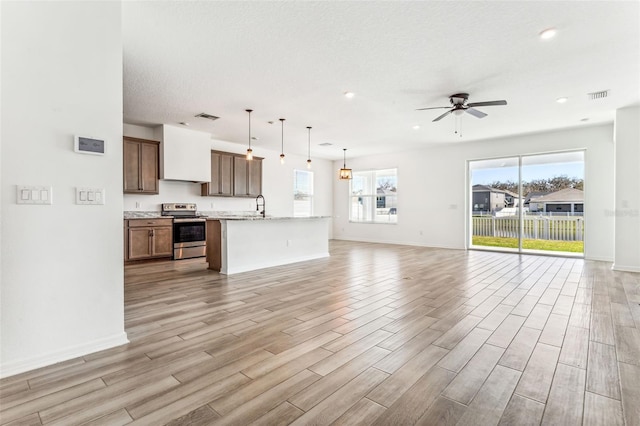 unfurnished living room featuring light wood-type flooring, visible vents, and a sink