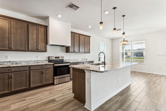 kitchen with visible vents, light wood-style flooring, light stone counters, stainless steel range with electric stovetop, and a sink