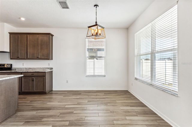 kitchen featuring dark brown cabinets, range with electric cooktop, visible vents, and light wood-style floors