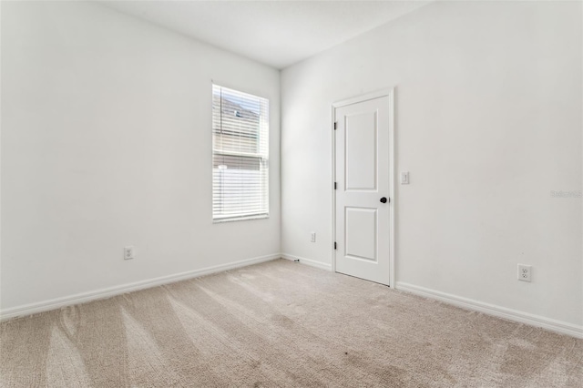 unfurnished room featuring light carpet and baseboards