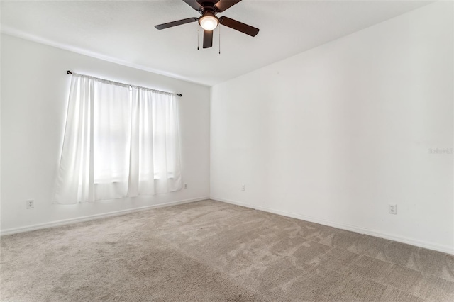 carpeted spare room featuring baseboards and a ceiling fan