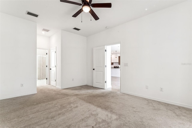 empty room featuring visible vents, a ceiling fan, and light colored carpet