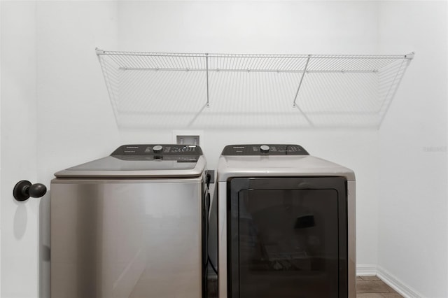 washroom with laundry area, baseboards, and washing machine and clothes dryer