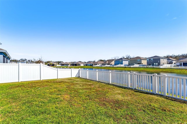 view of yard with a water view, a fenced backyard, and a residential view