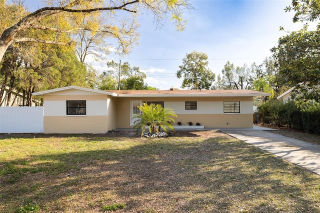 ranch-style home featuring brick siding, fence, and a front yard