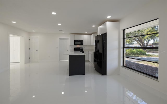 kitchen with recessed lighting, light countertops, white cabinets, a kitchen island, and black appliances