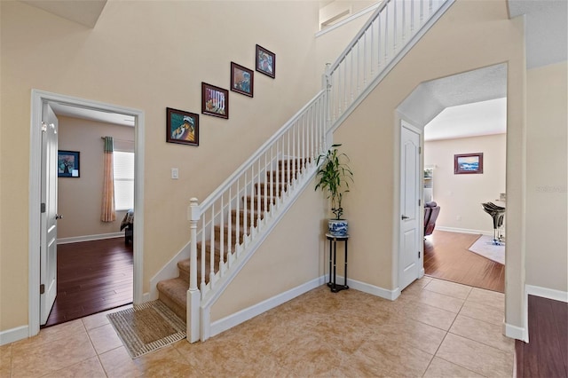 stairs featuring tile patterned flooring, baseboards, and a high ceiling