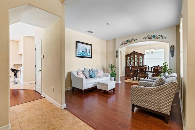 living area featuring light wood-type flooring, visible vents, arched walkways, and baseboards