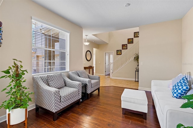 living area featuring stairs, baseboards, and wood finished floors