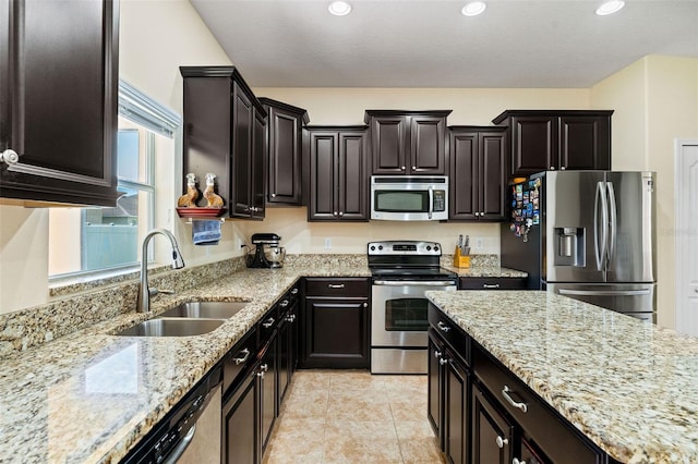 kitchen featuring light tile patterned floors, appliances with stainless steel finishes, light stone countertops, a sink, and recessed lighting