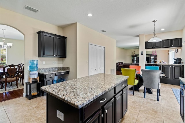 kitchen featuring a center island, visible vents, a notable chandelier, and dark cabinetry