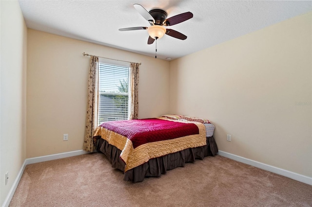 carpeted bedroom with ceiling fan, baseboards, and a textured ceiling