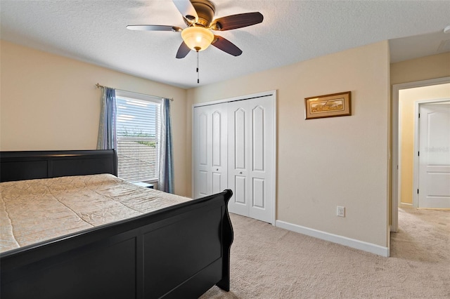 bedroom featuring light carpet, a textured ceiling, baseboards, and a closet