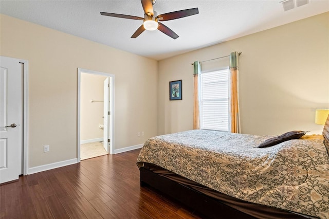 bedroom with ceiling fan, ensuite bathroom, dark wood-type flooring, visible vents, and baseboards