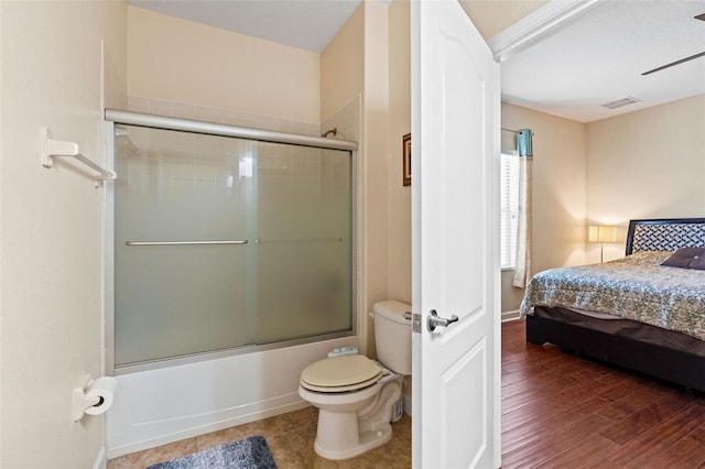 bathroom featuring visible vents, toilet, shower / bath combination with glass door, wood finished floors, and ensuite bathroom