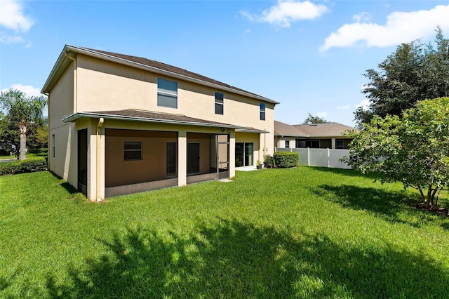 rear view of property featuring a yard, fence, and stucco siding