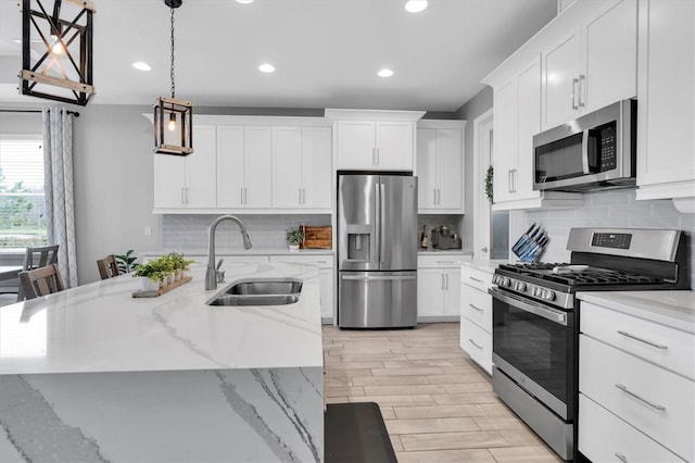 kitchen with stainless steel appliances, wood tiled floor, white cabinets, and a sink