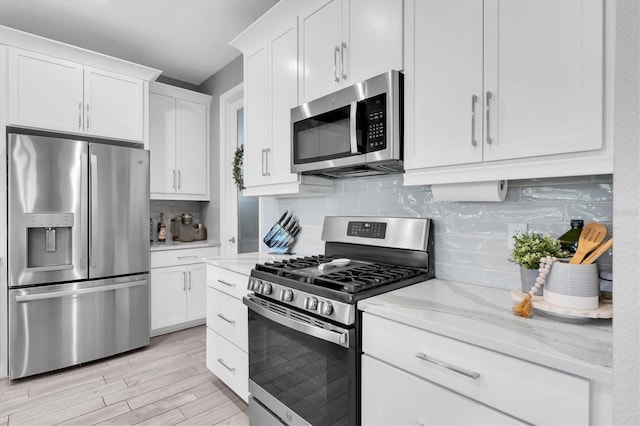 kitchen featuring appliances with stainless steel finishes, white cabinets, and tasteful backsplash