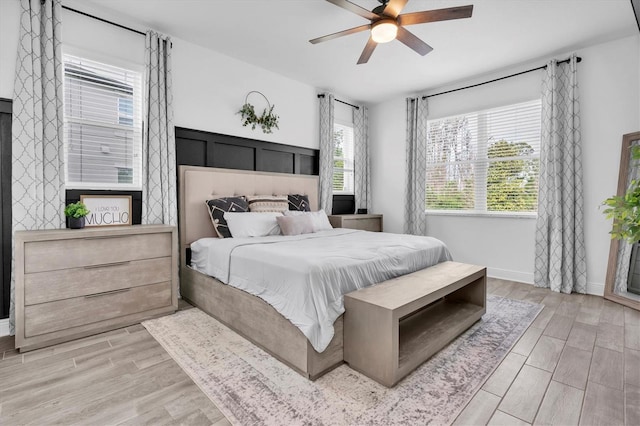 bedroom featuring a ceiling fan, baseboards, and light wood finished floors