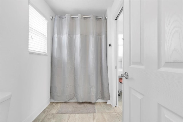 full bathroom with toilet, curtained shower, and tile patterned flooring