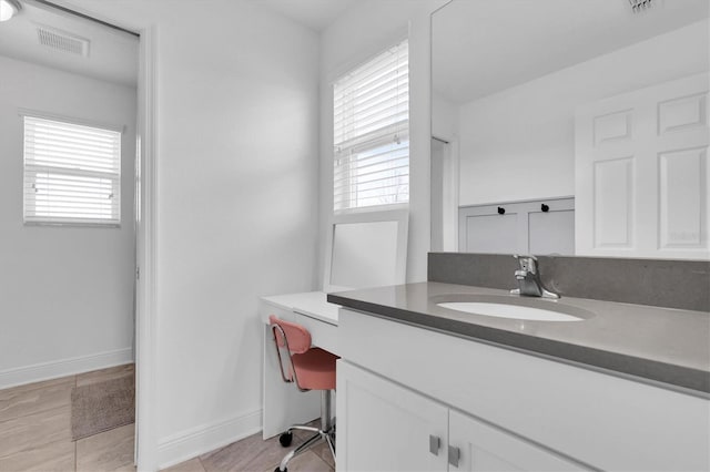 bathroom featuring visible vents, plenty of natural light, vanity, and baseboards