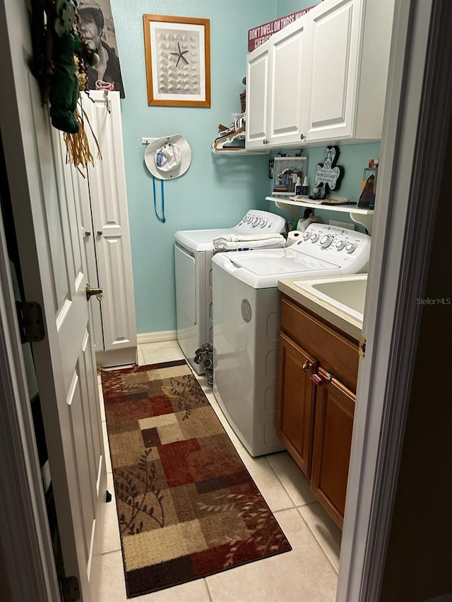 laundry area with light tile patterned floors, independent washer and dryer, and cabinet space