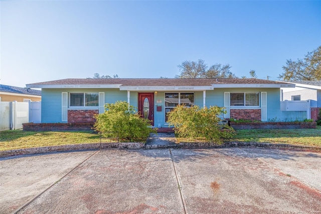 single story home with a front lawn, fence, and brick siding