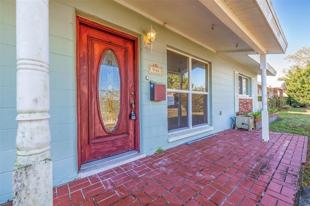 entrance to property with a porch and concrete block siding