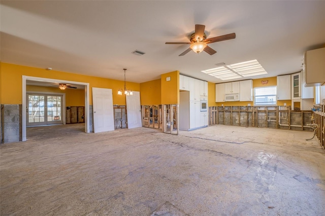 unfurnished living room featuring ceiling fan with notable chandelier and visible vents