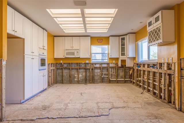 kitchen with a wealth of natural light, white appliances, visible vents, and a skylight