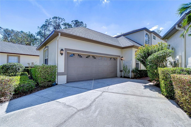 view of home's exterior with a garage, driveway, a shingled roof, and stucco siding