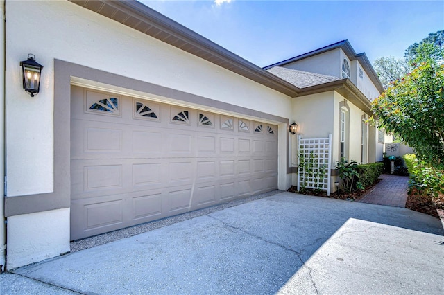 view of property exterior featuring concrete driveway, roof with shingles, and stucco siding