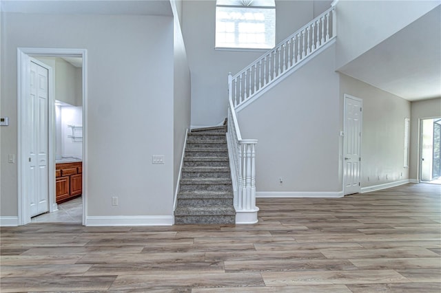 staircase with a towering ceiling, baseboards, and wood finished floors