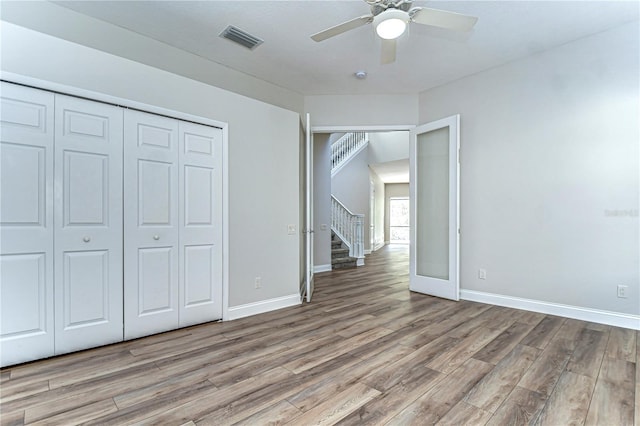 unfurnished bedroom featuring light wood-style flooring, a ceiling fan, visible vents, baseboards, and a closet