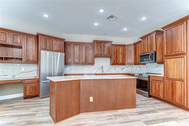 kitchen featuring a sink, a kitchen island, visible vents, appliances with stainless steel finishes, and light wood-type flooring