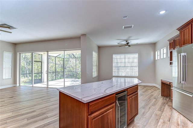 kitchen featuring light wood finished floors, beverage cooler, a wealth of natural light, and high end fridge