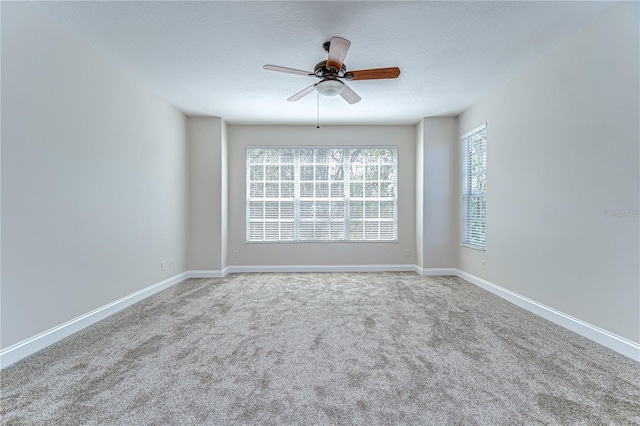 carpeted spare room featuring ceiling fan, a textured ceiling, and baseboards