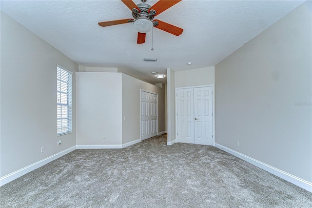 unfurnished bedroom with visible vents, a textured ceiling, baseboards, and two closets