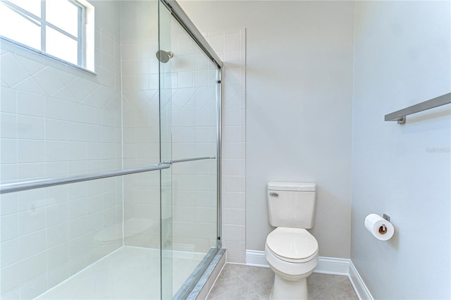 bathroom featuring a stall shower, tile patterned flooring, toilet, and baseboards