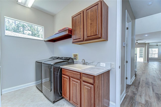 clothes washing area featuring ceiling fan, a sink, baseboards, independent washer and dryer, and cabinet space