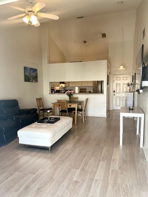 living area featuring visible vents, wood finished floors, high vaulted ceiling, and ceiling fan