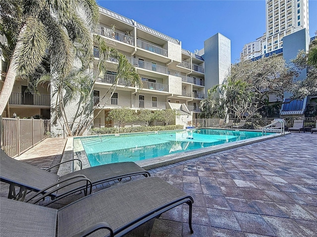 community pool with a patio area and fence