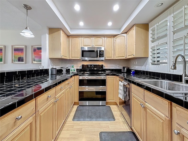 kitchen featuring light brown cabinetry, light wood-style flooring, appliances with stainless steel finishes, and a sink