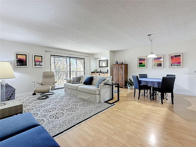 living room featuring light wood-style floors, baseboards, and a textured ceiling