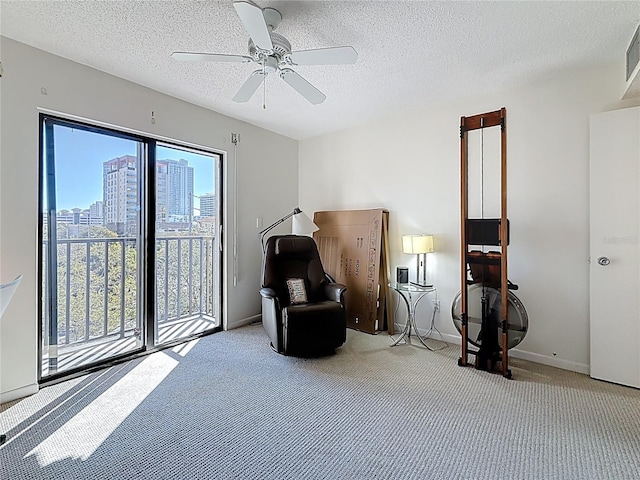 sitting room with a ceiling fan, baseboards, visible vents, carpet floors, and a textured ceiling